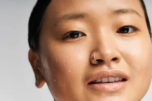 A radiant young Asian woman smiles confidently against a soft backdrop. — Stock Photo