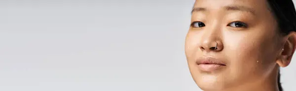 A confident young Asian woman stands against a neutral background, radiating elegance. — Stock Photo
