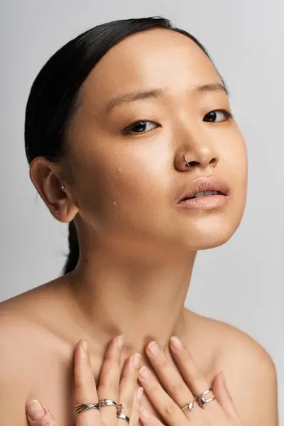 A young beautiful Asian woman gazes thoughtfully at the camera, showcasing her inner strength. — Stock Photo