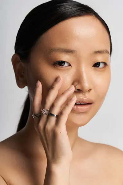 A young Asian woman touches her face, highlighting her beauty and confidence. — Stock Photo