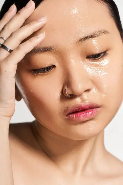 A young Asian woman savors a calming skincare treatment, embracing self care. — Stock Photo