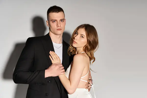 Hermosa novia y novio guapo abrazan de cerca, irradiando amor en un entorno moderno. - foto de stock