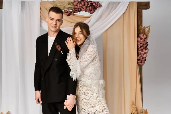 Une belle mariée en robe de dentelle se tient avec son beau marié, partageant un moment joyeux. — Photo de stock