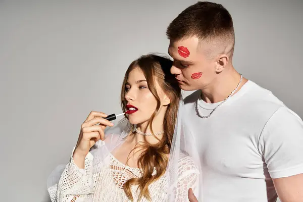 Young bride applies lipstick while groom admires her beauty, capturing the essence of love and joy. — Stock Photo