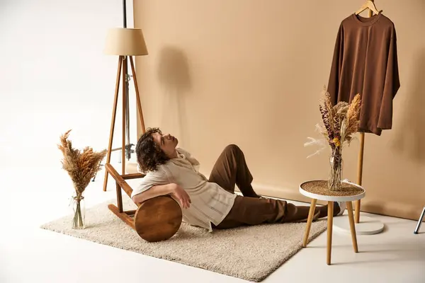 A young man with curly hair relaxes in a modern studio, showing off his stylish summer outfit. — Stock Photo