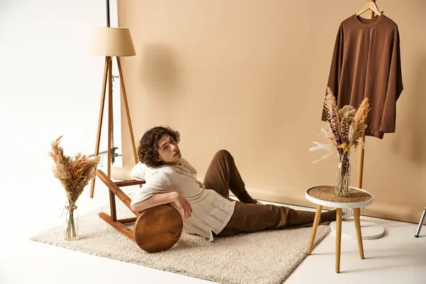 A good looking young man lounges comfortably in a stylish summer outfit surrounded by decor. — Stock Photo