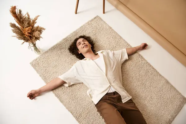 A good looking young man with curly hair lounges on a plush rug, showcasing his summer style. — Stock Photo