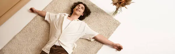 Un giovane uomo con i capelli ricci gode di un momento di relax in un elegante vestito estivo all'interno, banner — Foto stock
