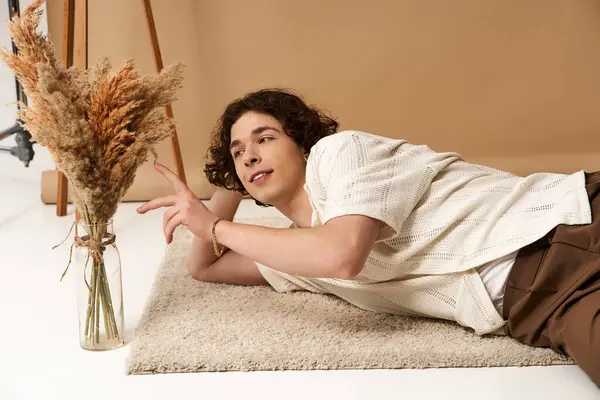 Good looking young man with curly hair lounges comfortably while showcasing a stylish summer outfit. — Stock Photo