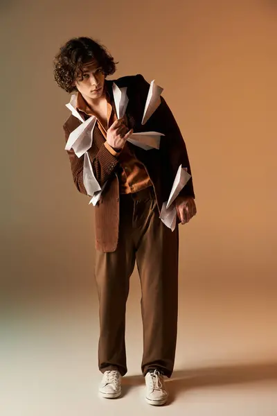 In a vibrant studio, a young man showcases his unique style with paper planes on a blazer. — Stock Photo