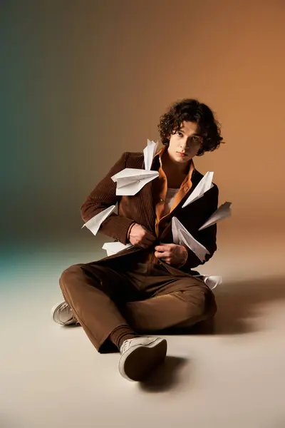 Young man showcases his unique style with paper planes adorning a brown corduroy blazer. — Stock Photo