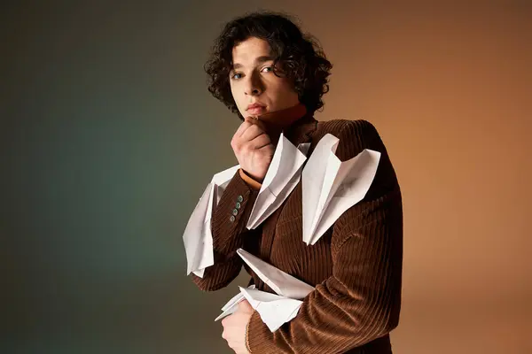A handsome young man in a curly hairstyle wears a stylish brown corduroy blazer with paper planes. — Stock Photo