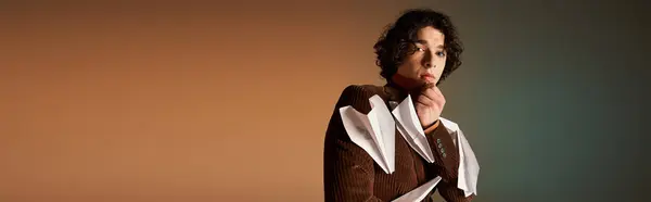 A young man with curly hair poses confidently in a brown corduroy blazer with paper planes, banner — Stock Photo