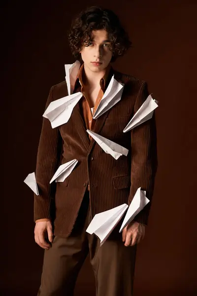 Jeune homme aux cheveux bouclés modèle un élégant blazer en velours côtelé marron orné d'avions en papier. — Stock Photo