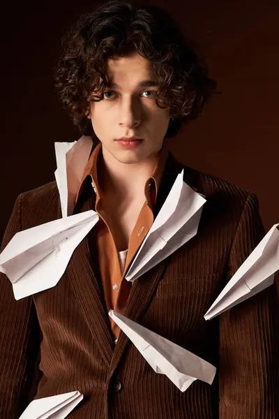 A fashionable young man stands confidently in a studio space adorned with paper planes. — Stock Photo