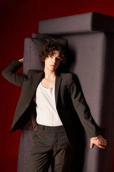 Um jovem com cabelo encaracolado faz uma pose relaxada em uma roupa preta contra um cenário vibrante. — Fotografia de Stock