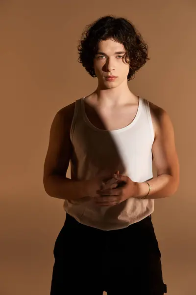A young man with curly hair in a stylish tank top exudes charm and confidence. — Stock Photo