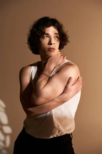 Good looking young man showcases his curly hair and stylish outfit while posing in a studio. — Stock Photo