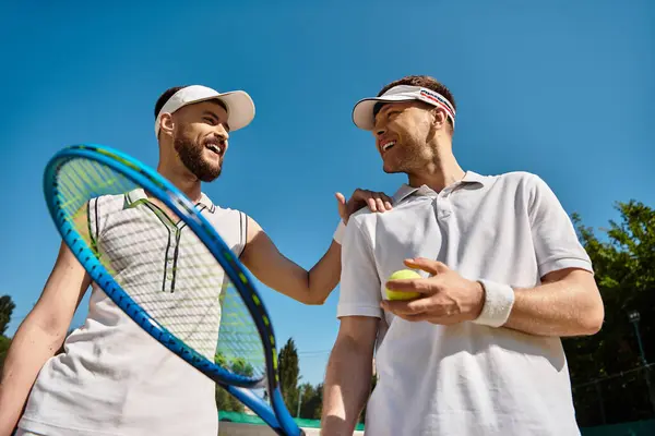 Two young men share joyful moments while playing tennis together during summer. — Stock Photo