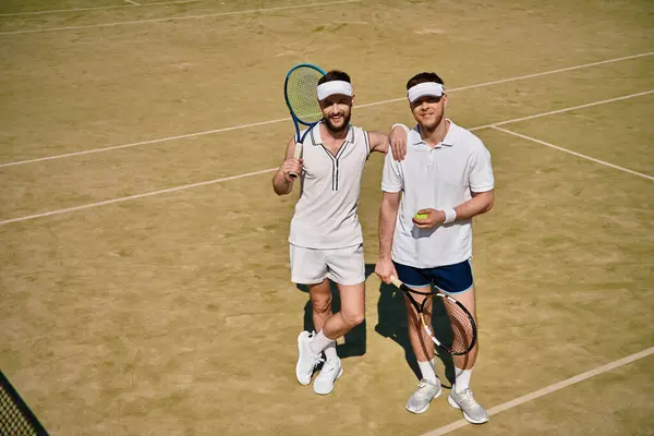 Two men share a joyful moment while playing tennis on a sunny summer day outdoors. — Stock Photo