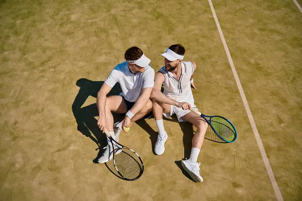 Two young men share a joyful moment while playing tennis on a warm summer day. — Stock Photo