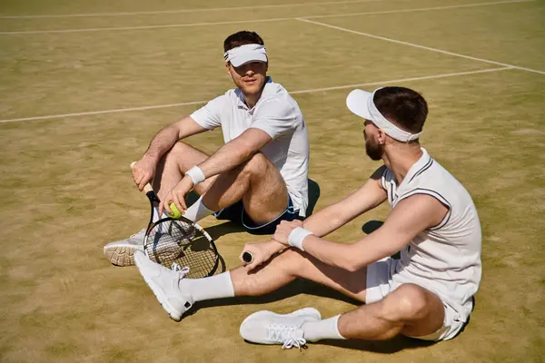 Two men relax and chat on a tennis court, enjoying their time together in summer sports. — Stock Photo