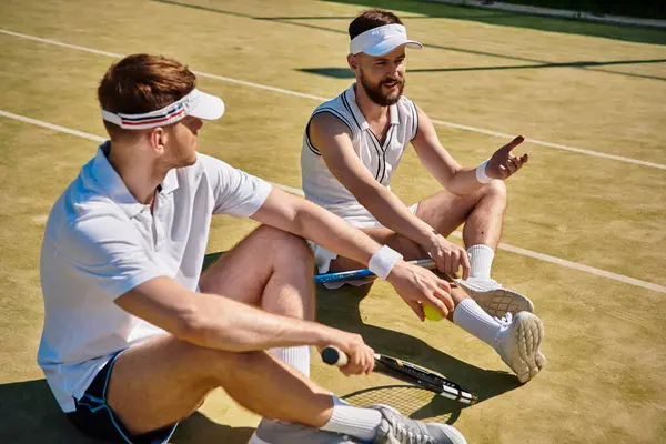 Two talented men enjoy a break while playing tennis on a sunny court with lively vibes. — Stock Photo