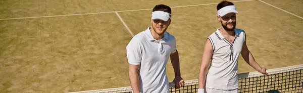 Dos hombres disfrutan de un animado juego de tenis en un soleado día de verano en la cancha, bandera - foto de stock