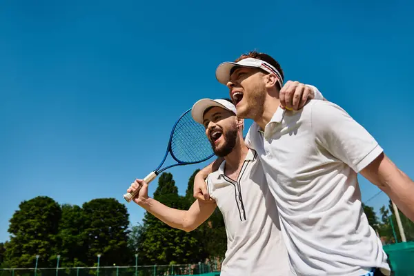 Two handsome men enjoy a spirited moment while playing tennis on a sunny day outdoors. — Stock Photo