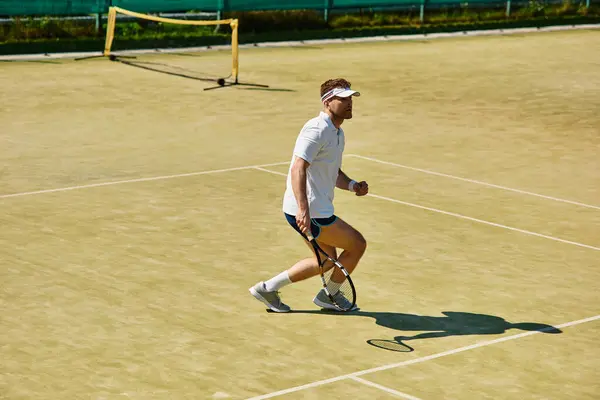 A man plays tennis energetically on a court under the warm summer sun. — Stock Photo