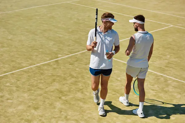 Two young men share laughter and joy while playing tennis on a summer day, creating memories. — Stock Photo