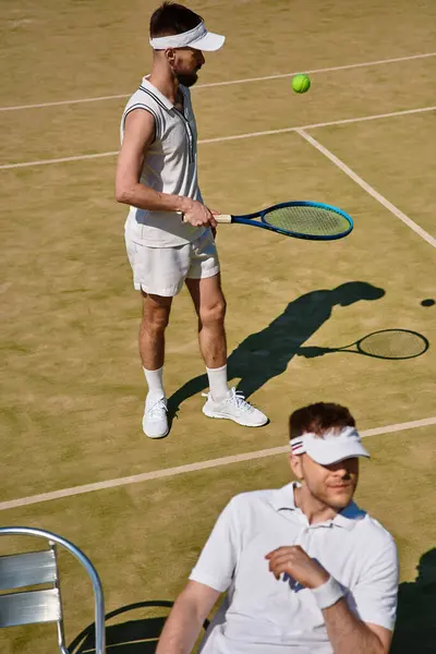 Dos hombres atléticos juegan al tenis bajo el cálido sol en una pista bien mantenida. - foto de stock