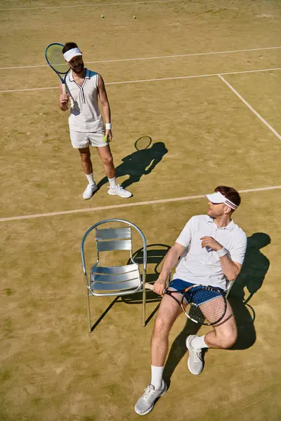 A young gay couple enjoys a vibrant summer day playing tennis on the court, sharing fun moments. — Stock Photo