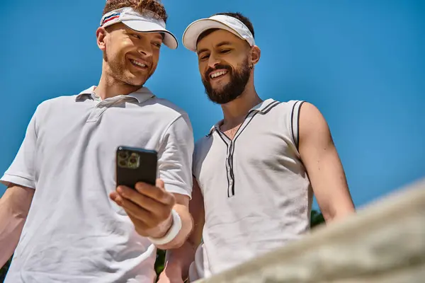 Due uomini giocano a tennis insieme e si divertono a fare una pausa, controllando i loro punteggi. — Foto stock