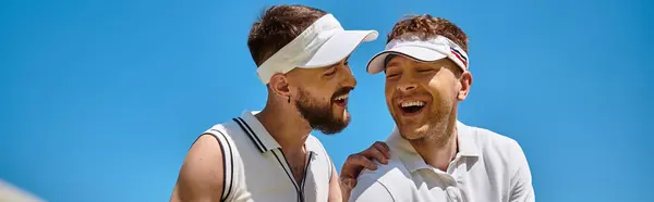 Two young men share a smiling moment while playing tennis, enjoying a sunny summer day, banner — Stock Photo