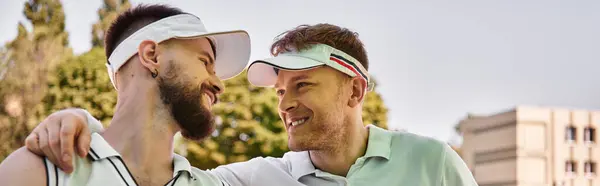 Two young men enjoy a playful tennis match under the warm summer sun, sharing smiles, banner — Stock Photo