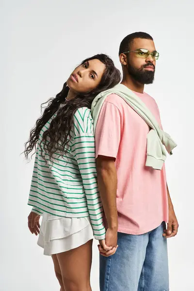 A fashionable couple stands back to back, radiating love and style with their trendy attire. — Stock Photo