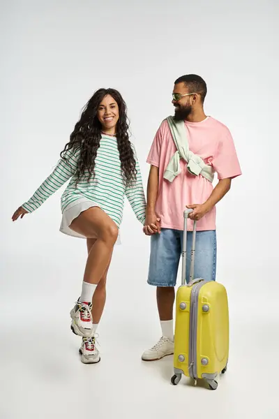 A cheerful couple shares a playful moment while preparing for a trip, showcasing their fashion. — Stock Photo