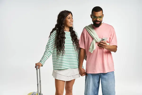 A stylish couple smiles at each other, holding hands and checking their phone in a cozy spot. — Stock Photo