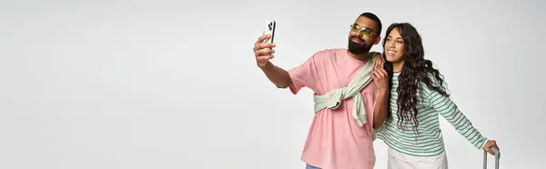 Una pareja de moda sonríe mientras se toma una selfie en un espacio contemporáneo, compartiendo vibraciones alegres. — Stock Photo