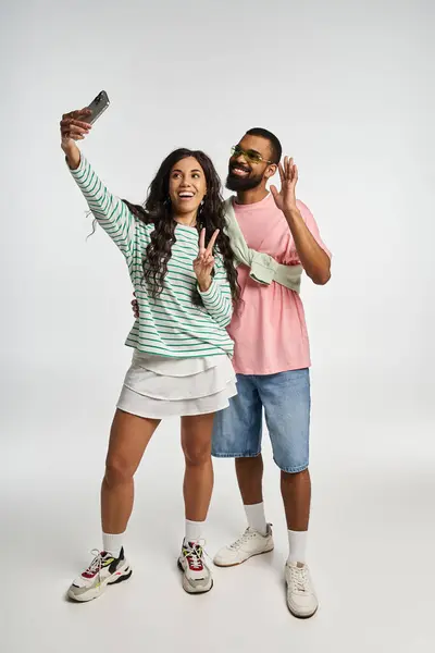 This trendy couple strikes a fun pose as they capture a lighthearted selfie indoors, radiating love. — Stock Photo