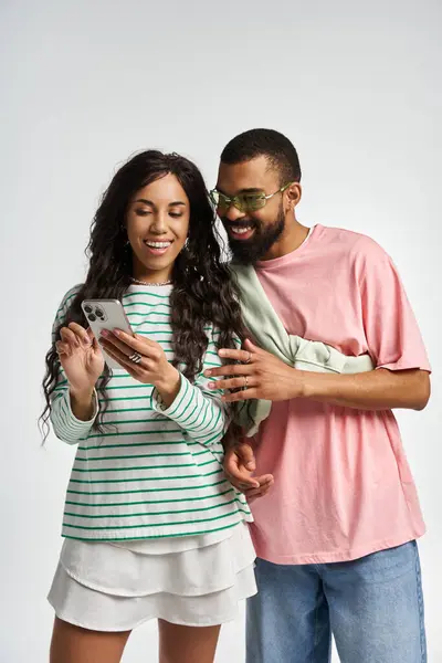 A fashionable couple enjoys a joyful moment together, exploring their phones content. — Stock Photo