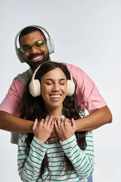 A fashionable couple shares a loving moment while listening to music, expressing happiness. — Stock Photo