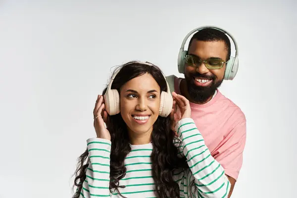 A fashionable couple shares a joyful moment, smiling while wearing stylish headphones. — Stock Photo