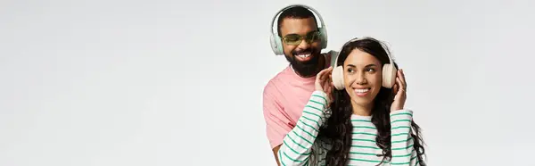 Una coppia alla moda condivide un momento gioioso, ascoltando musica sorridendo e abbracciando. — Foto stock