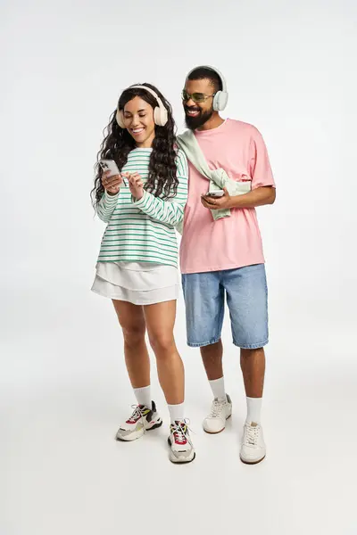 Um casal na moda compartilha um momento alegre ao ouvir música e se envolver com seus dispositivos. — Fotografia de Stock