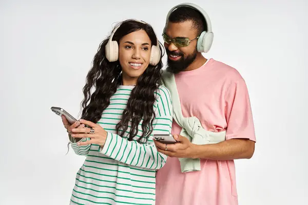 Fashionable pair shares a joyful moment, immersed in melodies with headphones on, smiling. — Stock Photo