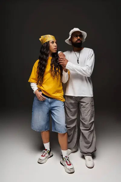 A fashionable couple stands side by side, flaunting vibrant attire and trendy accessories. — Stock Photo