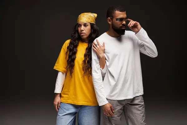 A fashionable couple stands together, expressing love and style in a studio with dramatic lighting. — Stock Photo