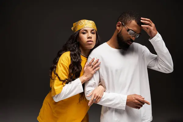A fashionable couple expresses love and connection against a dark, moody backdrop. — Stock Photo